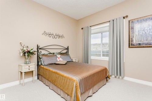 Carpeted bedroom featuring a window with blinds and drapes, a decorative metal headboard, and a built-in wall art piece - 116 Darlington Crescent, Edmonton, AB 