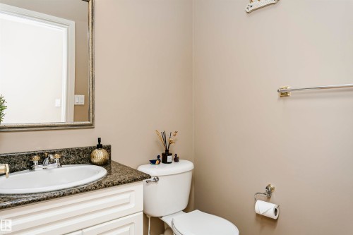 Bathroom featuring a white vanity with paneled cabinetry, a dark granite countertop, and an undermount sink with a brass-finish faucet - 116 Darlington Crescent, Edmonton, AB 