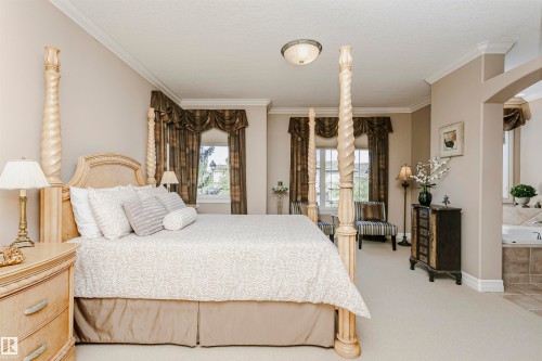 Spacious room featuring neutral carpeting, crown molding, and an arched entry to a tiled area with a built-in tub - 116 Darlington Crescent, Edmonton, AB 