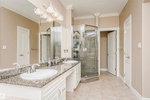 Spacious bathroom featuring a double vanity with granite countertops, dual undermount sinks, a corner glass-enclosed shower, and tile flooring - 116 Darlington Crescent, Edmonton, AB 