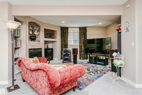Open concept living area featuring a built-in fireplace with tile surround, recessed lighting, and a window with patterned drapes - 116 Darlington Crescent, Edmonton, AB 