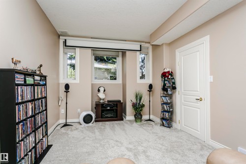 Carpeted room featuring neutral wall tones, two windows with white trim, a white paneled door, and a ceiling-mounted projection screen - 116 Darlington Crescent, Edmonton, AB 