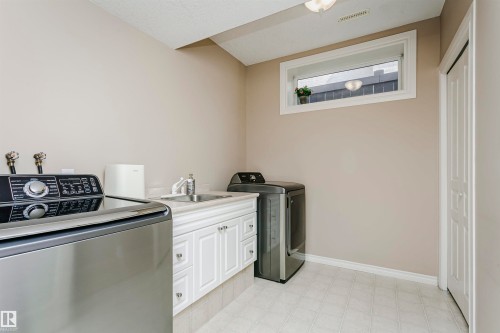 Laundry area featuring white cabinetry, a utility sink, and light-toned flooring - 116 Darlington Crescent, Edmonton, AB 