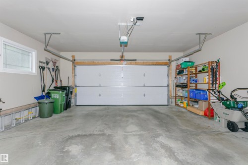 Attached double garage featuring a paneled white door, a single window, and concrete flooring - 116 Darlington Crescent, Edmonton, AB 