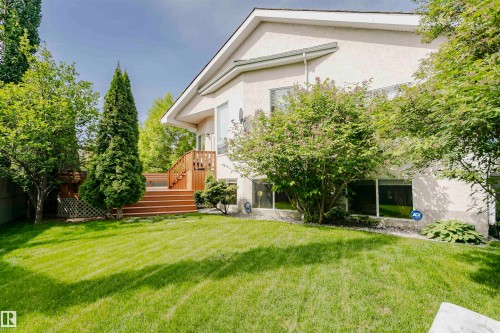Expansive rear yard featuring a manicured lawn, multi-level wood deck, and mature trees - 116 Darlington Crescent, Edmonton, AB 