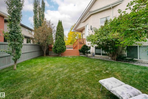 Expansive backyard featuring a manicured lawn, a multi-tiered wood deck, mature trees, and a privacy fence - 116 Darlington Crescent, Edmonton, AB 