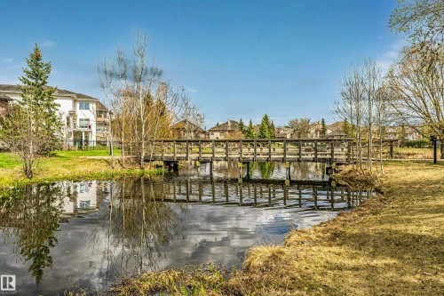 Waterfront setting featuring a wooden pedestrian bridge, calm water, and mature trees - 116 Darlington Crescent, Edmonton, AB 