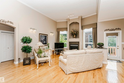 Vaulted living area featuring light wood-finish flooring, a contemporary fireplace with a stone surround, and abundant natural light from multiple windows - 116 Darlington Crescent, Edmonton, AB 
