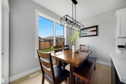 Dining area featuring a contemporary linear chandelier, light wood-finish flooring, and a large window - 