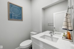 Bathroom featuring a white vanity with an integrated rectangular sink, chrome faucet, and expansive mirror - 