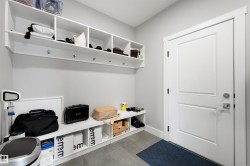 Entryway featuring a built-in storage system with open shelving, coat hooks, and a bench - 