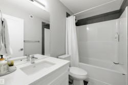 Bathroom featuring a white vanity with an integrated sink, polished chrome faucet, and a large wall-mounted mirror - 