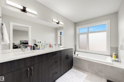 Dual vanity with quartz countertop, wood-finish cabinetry, and integrated sinks - 