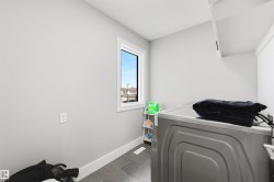 Utility room featuring tile flooring, white baseboards, and a window with white trim - 