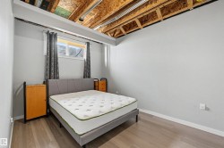 Bedroom featuring wood-finish flooring, a window with horizontal blinds, and a neutral wall color - 