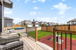 Spacious rear deck featuring light-toned wood planks and dark metal balusters - 
