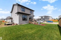 Lawned backyard with a wooden deck and a ground-level patio space - 
