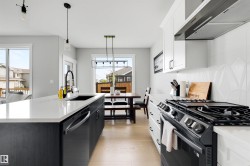 Open-concept kitchen featuring an expansive island with a built-in sink, white countertops, and light wood-finish flooring - 