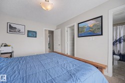 Bedroom featuring light neutral wall paint, wood-finish flooring, a flush-mount ceiling light fixture, and a white interior door - 