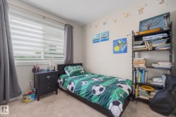 Carpeted bedroom featuring a large window with horizontal blinds and full-length gray drapes - 