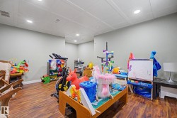 Spacious room featuring wood-finish flooring, recessed lighting, neutral wall tones, and a drop ceiling - 