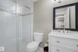 Bathroom featuring a glass-enclosed shower with subway tile surround, a single vanity with a white countertop, and a framed mirror - 