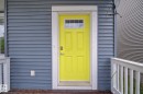 Bold yellow entry door with transom window set against horizontal gray siding - 3343 Weidle Way, Edmonton, AB 