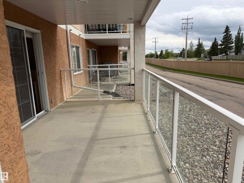 Concrete patio featuring glass panel railing with white framing - 118 7801 Golf Course Road, Stony Plain, AB 