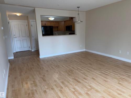 Spacious living area featuring light wood-finish flooring and neutral wall tones - 118 7801 Golf Course Road, Stony Plain, AB 