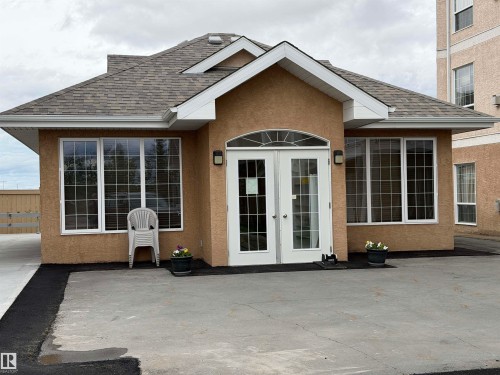 Stucco exterior building with a prominent arched double-door entry - 118 7801 Golf Course Road, Stony Plain, AB 