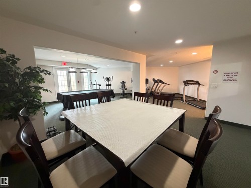 Dedicated amenity space featuring a central square table with four chairs, recessed lighting, and green carpet flooring - 118 7801 Golf Course Road, Stony Plain, AB 