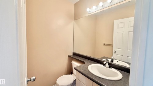 Bathroom featuring a single vanity with an integrated sink, dark countertop, and a large wall-mounted mirror - 9 225 Blackburn Drive E, Edmonton, AB 