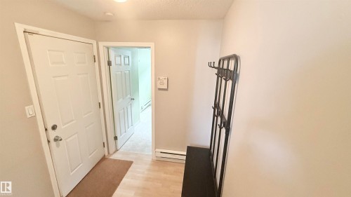 Entryway featuring light wood-finish flooring, neutral wall tones, and a six-panel exterior door - 9 225 Blackburn Drive E, Edmonton, AB 