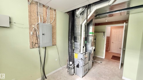 Utility area featuring a furnace system, exposed ductwork, and an electrical panel mounted on an OSB board - 9 225 Blackburn Drive E, Edmonton, AB 