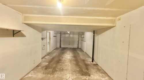 Attached garage space featuring a concrete floor, overhead lighting, and white walls - 9 225 Blackburn Drive E, Edmonton, AB 