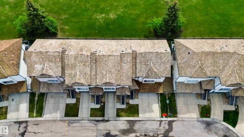 Row of townhomes featuring cedar shake roofing, concrete driveways, and individual street-facing entrances - 9 225 Blackburn Drive E, Edmonton, AB 