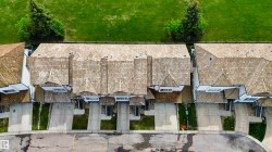 Row of townhomes featuring cedar shake roofing, concrete driveways, and individual street-facing entrances - 