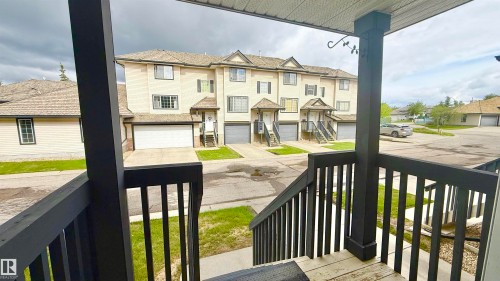 Multi-level townhouse exterior featuring light-colored siding, a gabled roof, and individual garage access - 9 225 Blackburn Drive E, Edmonton, AB 