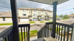 Multi-level townhouse exterior featuring light-colored siding, a gabled roof, and individual garage access - 