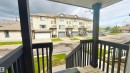 Multi-level townhouse exterior featuring light-colored siding, a gabled roof, and individual garage access - 9 225 Blackburn Drive E, Edmonton, AB 
