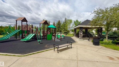 Community playground featuring multi-level play structures, slides, and a shaded stone-clad gazebo with built-in benches - 9 225 Blackburn Drive E, Edmonton, AB 