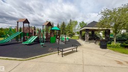 Community playground featuring multi-level play structures, slides, and a shaded stone-clad gazebo with built-in benches - 