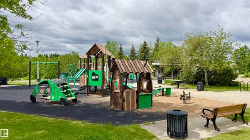Outdoor play area featuring multiple structures, including slides and swings, set on a dark rubberized surface - 9 225 Blackburn Drive E, Edmonton, AB 