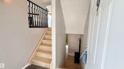 Entryway featuring light wood-finish stairs with dark balusters, gray wall paint, and dark tile flooring - 
