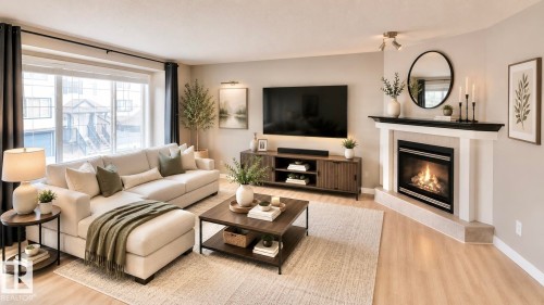 Living area featuring a corner fireplace with a white mantel and black surround, large windows with dark drapery, light wood-finish flooring, and neutral wall tones - 9 225 Blackburn Drive E, Edmonton, AB 