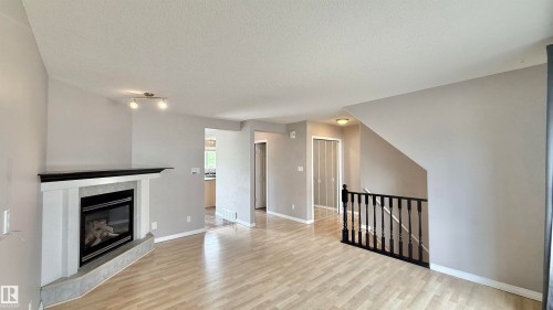Corner fireplace with a black mantel and light grey tile surround - 9 225 Blackburn Drive E, Edmonton, AB 