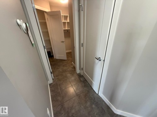 Hallway with durable tile flooring and painted walls - 6821 Evans Wynd, Edmonton, AB 
