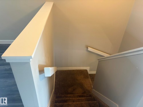 Carpeted staircase with white handrails and painted walls - 6821 Evans Wynd, Edmonton, AB 