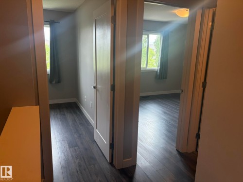Wood-finish flooring extends throughout multiple rooms, complemented by neutral wall tones and white trim - 6821 Evans Wynd, Edmonton, AB 