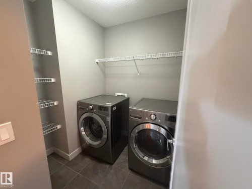 Dedicated laundry area featuring durable tile flooring and wire shelving systems - 6821 Evans Wynd, Edmonton, AB 